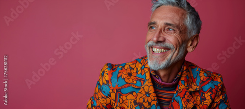 A man with a beard and mustache is smiling and wearing a colorful outfit. Concept of happiness and positivity. Happy elderly fashion model with grey full hair, mature and happy smiling man
