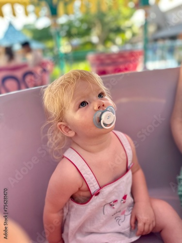 Enfant fille de 1 an et demi émerveillée par les couleurs d'un manège