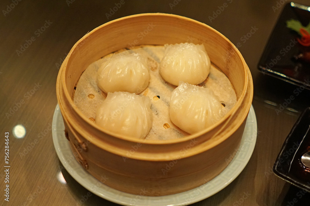 Close up Chinese 'Har Gow' Dim Sum, Steamed dumplings filled with minced pork, shrimp or others served in wooden basket container Close up Chinese 'Har Gow' Dim Sum, Steamed dumplings filled with minced pork, shrimp or others served in wooden basket container