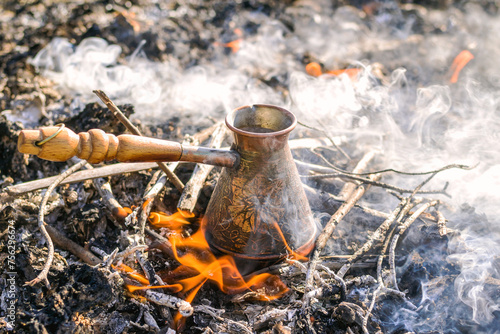 Making coffee in cezve on the bonfire when camping or hiking in the nature. Coffee on campfire.