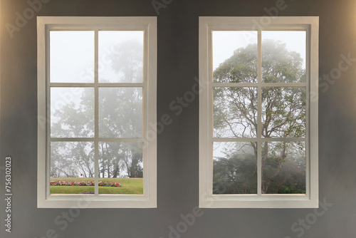 Interior image of English home style show two windows in warm living room see through the landscape natural view of big trees outsite in winter season.