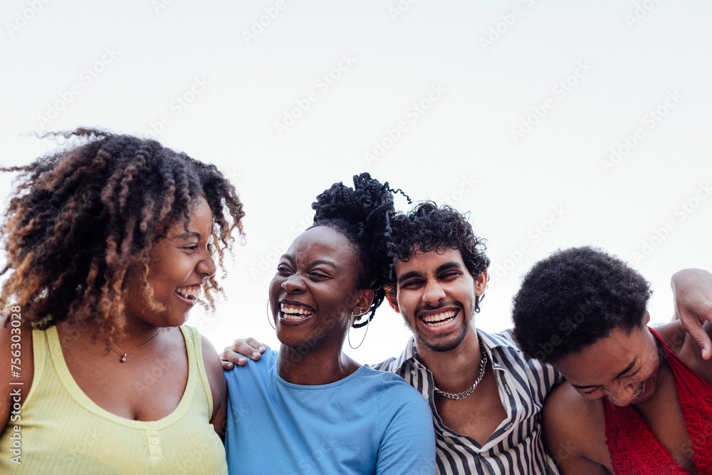 Four smiling mixed race friends standing and looking down at camera Four smiling mixed race friends standing and looking down at camera
