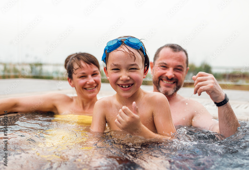 Cute boy and his parents are swimming in a Jacuzzi and an open-air pool. Cute boy and his parents are swimming in a Jacuzzi and an open-air pool.