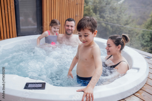 Happy family with two small children have fun in the jacuzzi photo