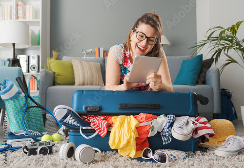 Woman preparing her luggage and connecting online photo