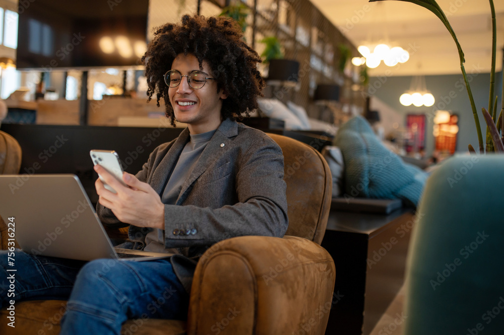 Young man with laptop looking contented and smiling Young man with laptop looking contented and smiling