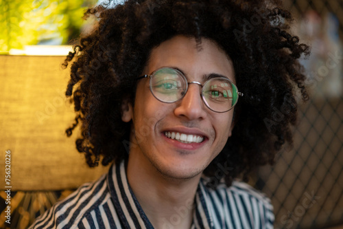 Portrait of a young smiling curly-haired man in eyeglasses