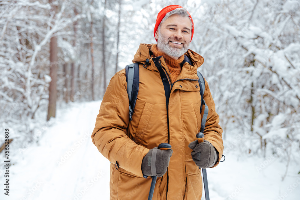 Smiling mature man in red hat in a snowy forest