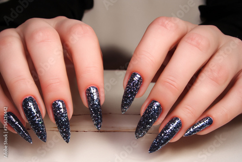 fashionable manicure. long dark shiny nails on female hands, close-up view, beauty concept