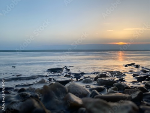 Sunset over the sea.The gentle rays of the setting sun caress the surface of the boundless sea, imparting soft hues of warmth and tranquility to the stones. Through the warm reflections of the evening
