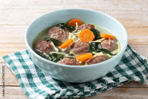 Italian Wedding Soup with meatballs and spinach on  wooden table