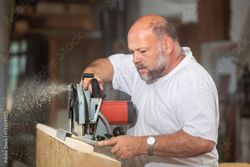 Tischler in seiner Werkstatt arbeitet mit Handkreissäge