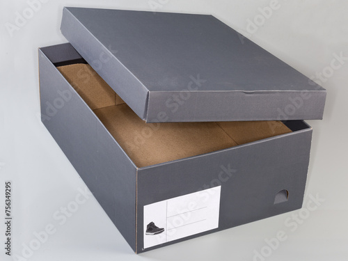 Empty partly open gray cardboard shoebox on light gray background