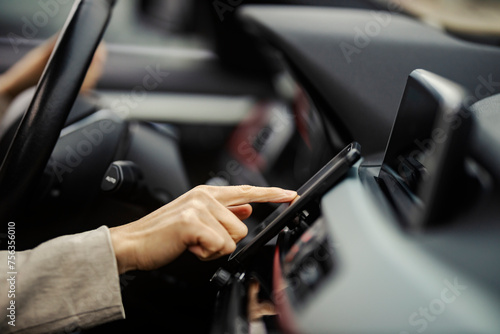 Close up of woman's hand typing navigation on cellphone in a car.