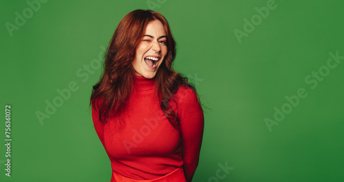 Joyful woman with sweater and nose ring standing on vibrant green background