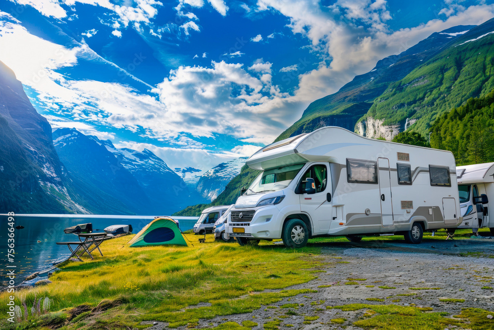 Stunning landscape featuring a luxury motorhome by a lakeside, with towering mountain ranges in the distance