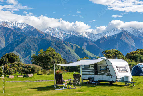 An idyllic caravan setup with chairs facing a stunning view of snow-capped mountains, great for outdoorsy holidaymakers and explorers photo