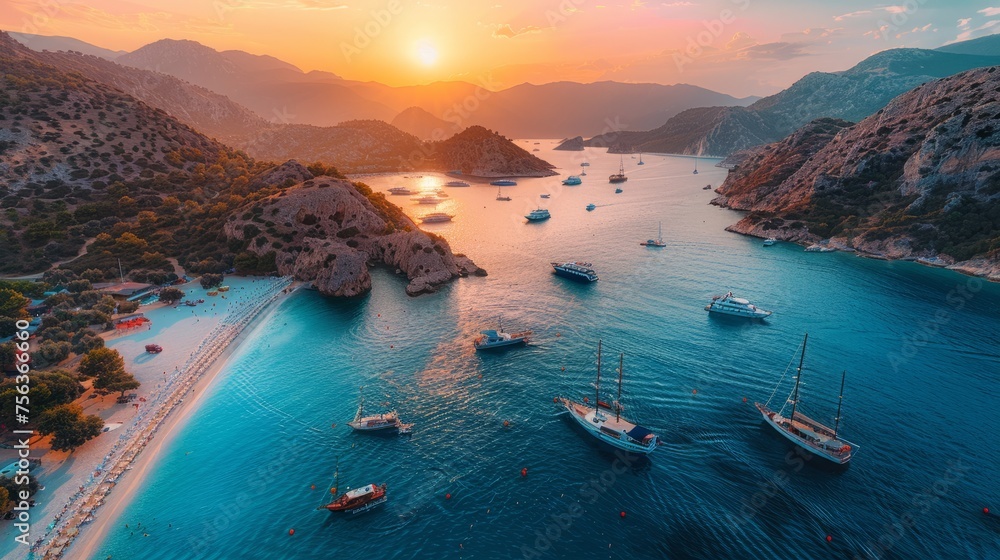 Aerial view of colorful ships parked on the beach in sunset, on the surface of the clear azure sea water in the Mediterranean sea. View from a drone