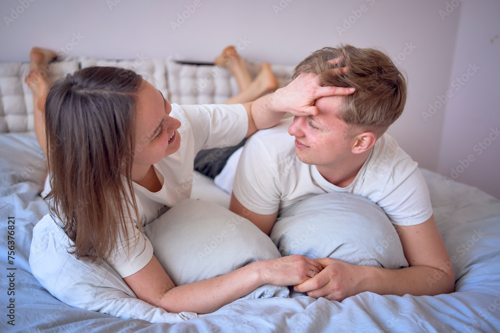 a young beautiful couple hugging and kissing in bed, wellness at home a young beautiful couple hugging and kissing in bed, wellness at home
