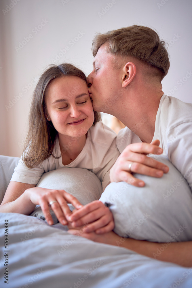 a young beautiful couple hugging and kissing in bed, wellness at home a young beautiful couple hugging and kissing in bed, wellness at home