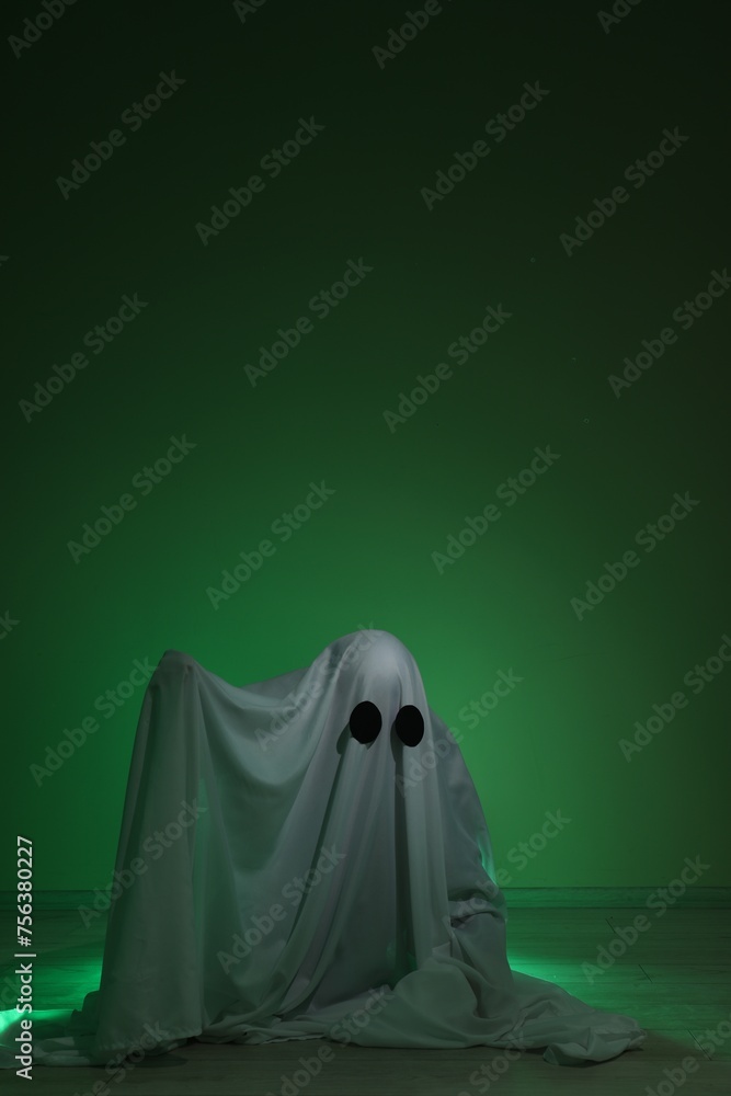 Creepy ghost. Woman covered with sheet in green light, space for text Creepy ghost. Woman covered with sheet in green light, space for text