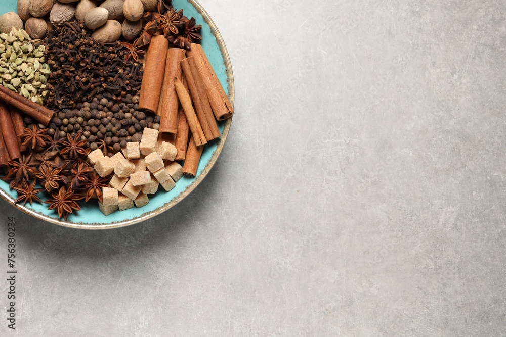Different spices and nuts in bowl on light gray textured table, top view. Space for text Different spices and nuts in bowl on light gray textured table, top view. Space for text