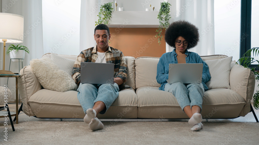 Busy husband and wife concentrate freelance workers gamers internet addict African American couple spouses family girlfriend boyfriend at home couch sofa man woman using laptops computers together Busy husband and wife concentrate freelance workers gamers internet addict African American couple spouses family girlfriend boyfriend at home couch sofa man woman using laptops computers together