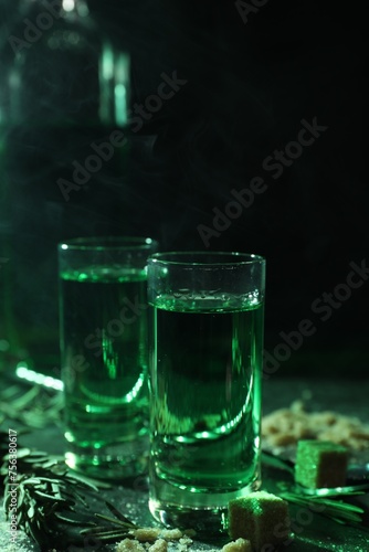 Absinthe in shot glasses, rosemary and brown sugar on table, closeup. Alcoholic drink