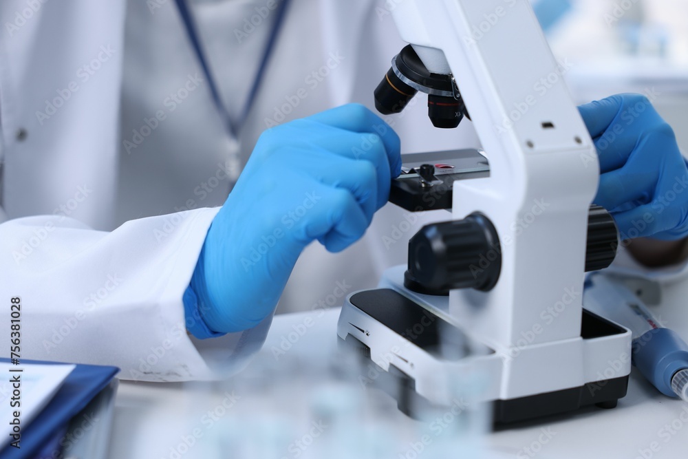 Scientist working with microscope in laboratory, closeup Scientist working with microscope in laboratory, closeup