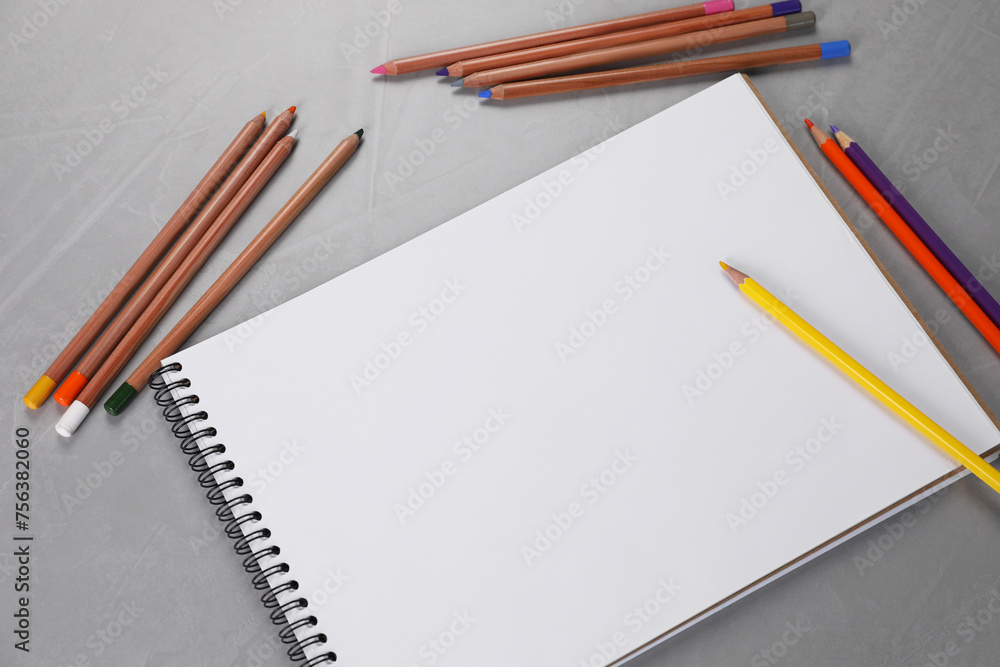 Empty sketchbook and colorful pencils on grey textured table, flat lay Empty sketchbook and colorful pencils on grey textured table, flat lay