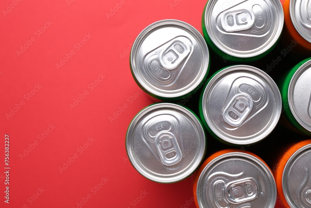 Energy drink in cans on red background, top view. Space for text Energy drink in cans on red background, top view. Space for text