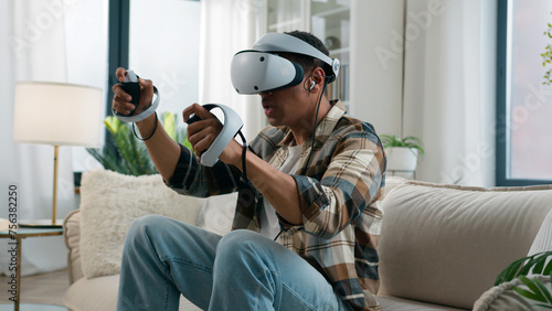 African American man player enjoying at home couch playing vr game fight boxing ethnic guy gamer male play online fighting wear headphones virtual reality 3d helmet glasses hold controllers joysticks