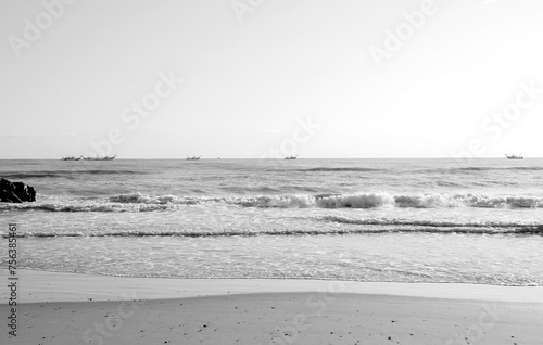 Deserted sandy beach in the morning on the Adriatic Sea with fishing boats under cloudless sky in Black and White	