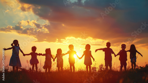 A group of children are holding hands in a field at sunset