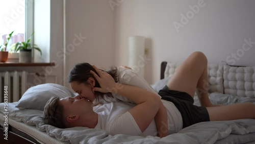 young couple on bed in bedroom gently cuddling