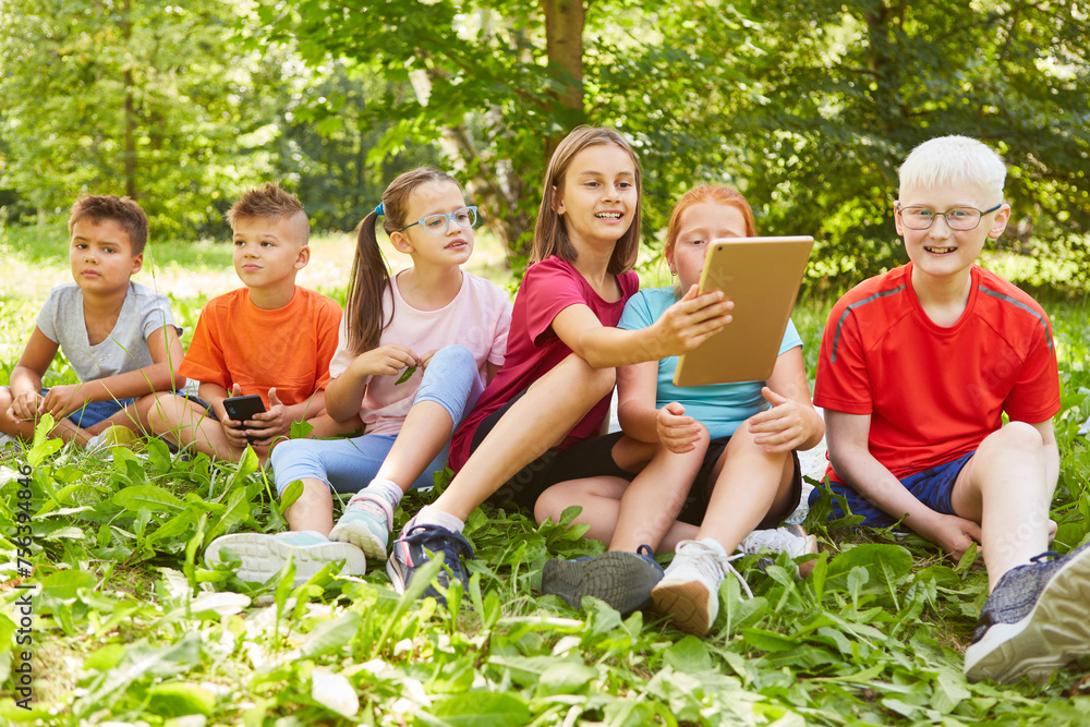 Girl holding tablet PC while sitting with friends Girl holding tablet PC while sitting with friends