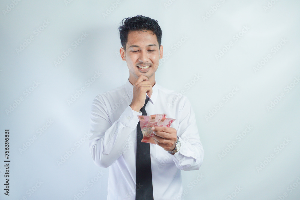 Adult Asian man doing thinking gesture while holding Indonesia paper money Adult Asian man doing thinking gesture while holding Indonesia paper money
