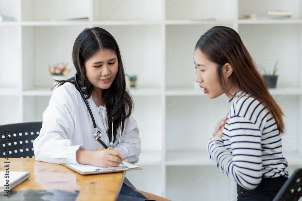 Attentive female doctor taking notes while consulting a patient in a modern medical office. Attentive female doctor taking notes while consulting a patient in a modern medical office.