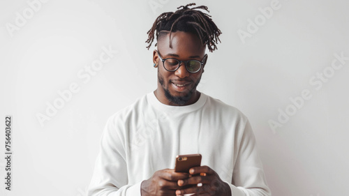 Trendy man with sunglasses smiling as he reads on his phone against a white background.