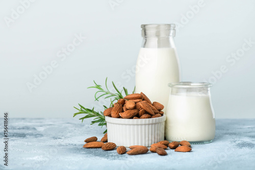 Almond lactose-free milk in bottles and almonds close-up on blue background