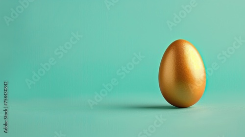 Single golden egg on a teal background, minimalist concept of wealth