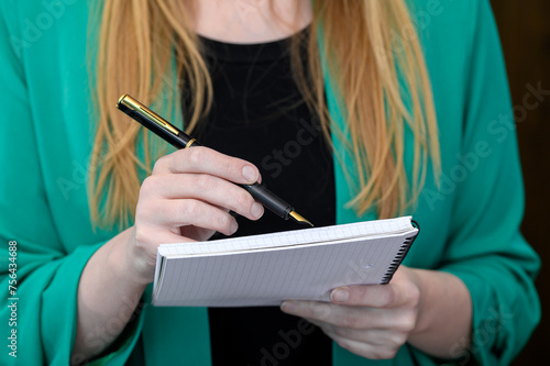 Kobieta notuje coś w zeszycie, zapisuje dlugopisem
