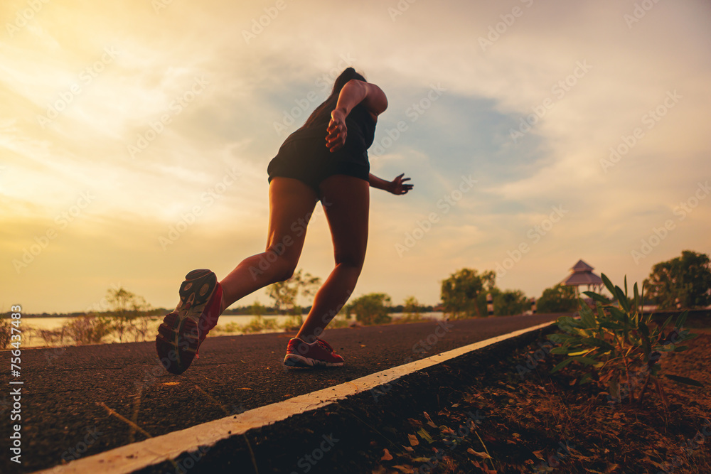 Silhouette of young woman running sprinting on road. Fit runner fitness runner during outdoor workout. Selected focus