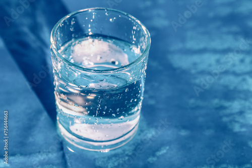 A glass of drinking water on blue background. Splashing water from glass