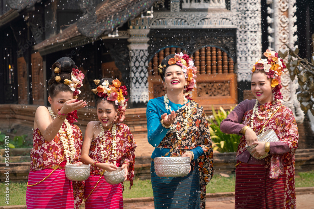 Group of Beautiful Lanna Asian woman wearing Thai costumes having fun splashing water to each other on Songkran festival. 