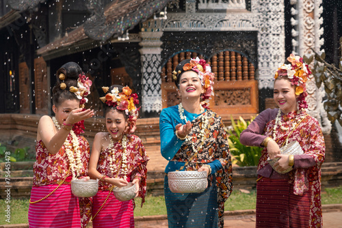 Group of Beautiful Lanna Asian woman wearing Thai costumes having fun splashing water to each other on Songkran festival. 