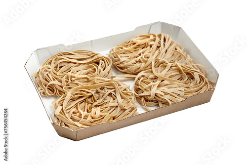 Whole grain pasta tagliatelle isolated on white background. Tagliatelle integrali in tray, wholemeal pasta photo