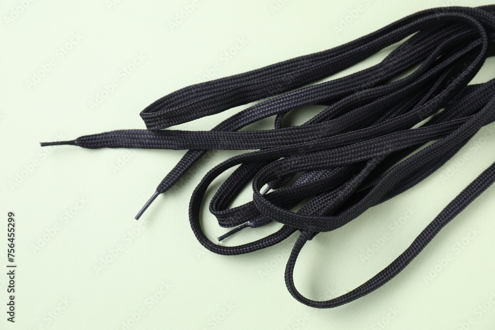 Stylish black shoe laces on light olive background, top view Stylish black shoe laces on light olive background, top view