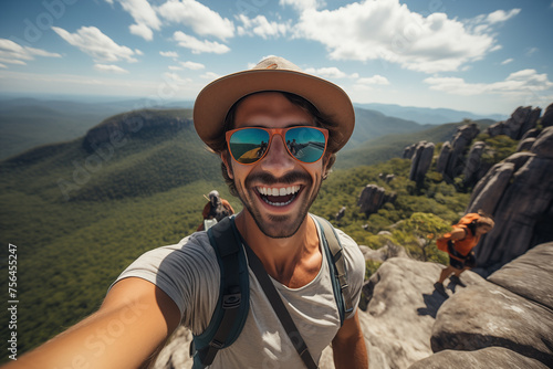 Joyful male hiker takes a selfie with expansive mountain views in the background