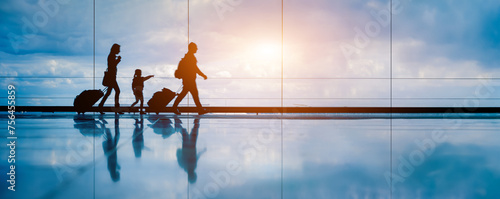 Family at airport travelling with young child walking to departure gate. Family vacation and holidays concept with silhouette of parents and kid. Travel lifestyle banner or background for air travel. photo